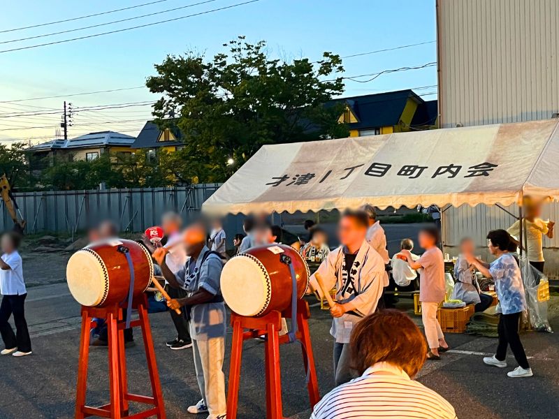 才津1丁目町内会のテント前に据えられた2台の太鼓を打つ人たち