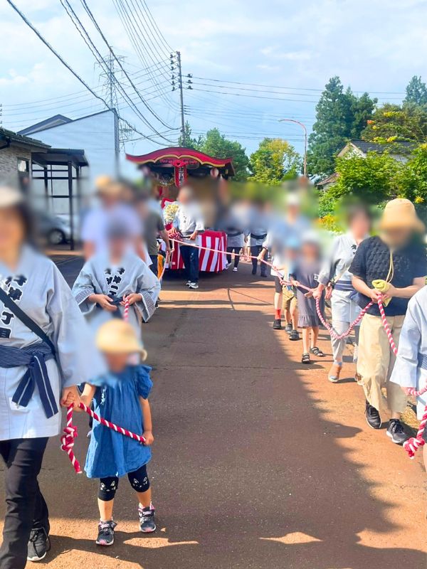 才津1丁目夏まつりの屋台巡行。紅白の綱を引いて町内を進む法被姿の大人と子どもたち