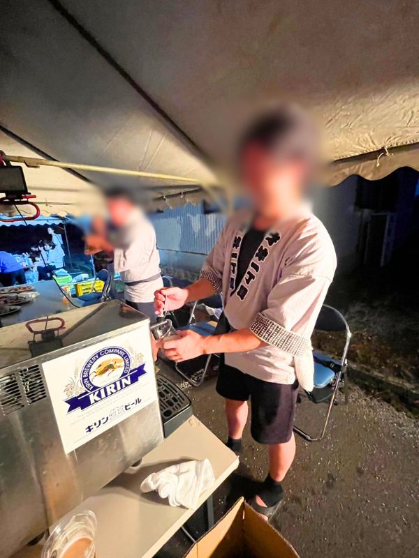 テントの下でビールサーバーから生ビールを注ぐ法被姿の男性